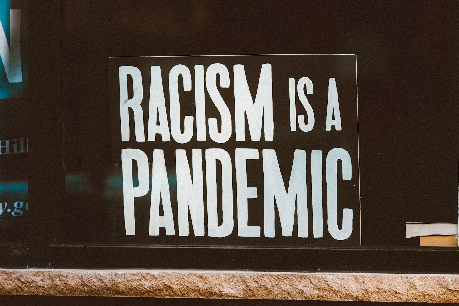 Black and white sign stating "RACISM IS A PANDEMIC"